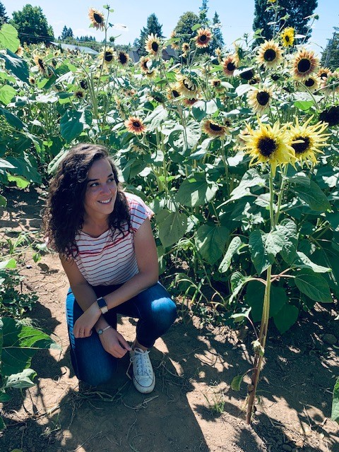 Imagen de una mujer parada junto a girasoles.