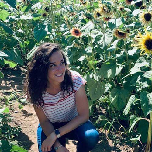 Picture of a woman standing next to sunflowers