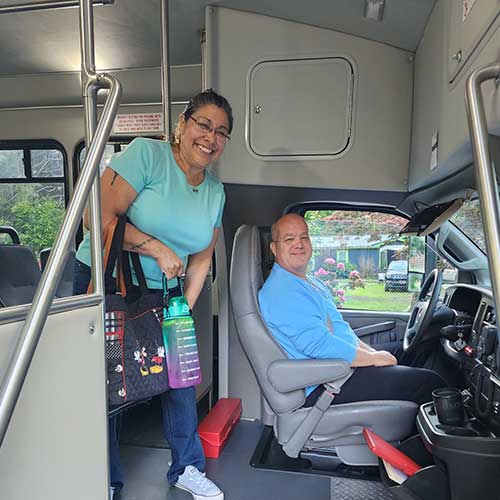 Person standing on bus next to bus driver