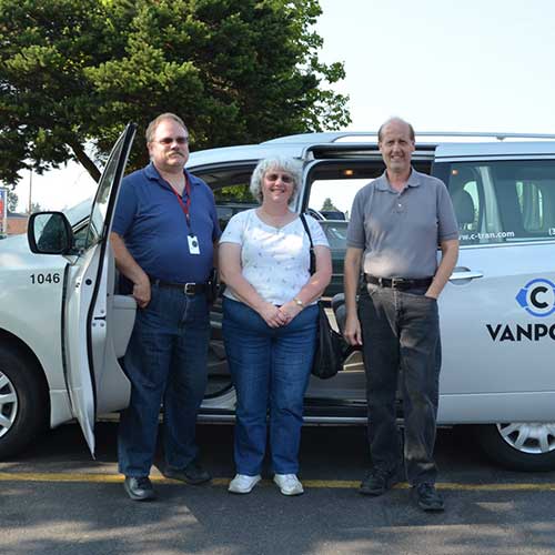 Three people stand outside of a C-Tran vanpool