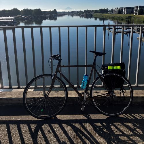A picture of a bike on a bridge with water and a mountain in the background